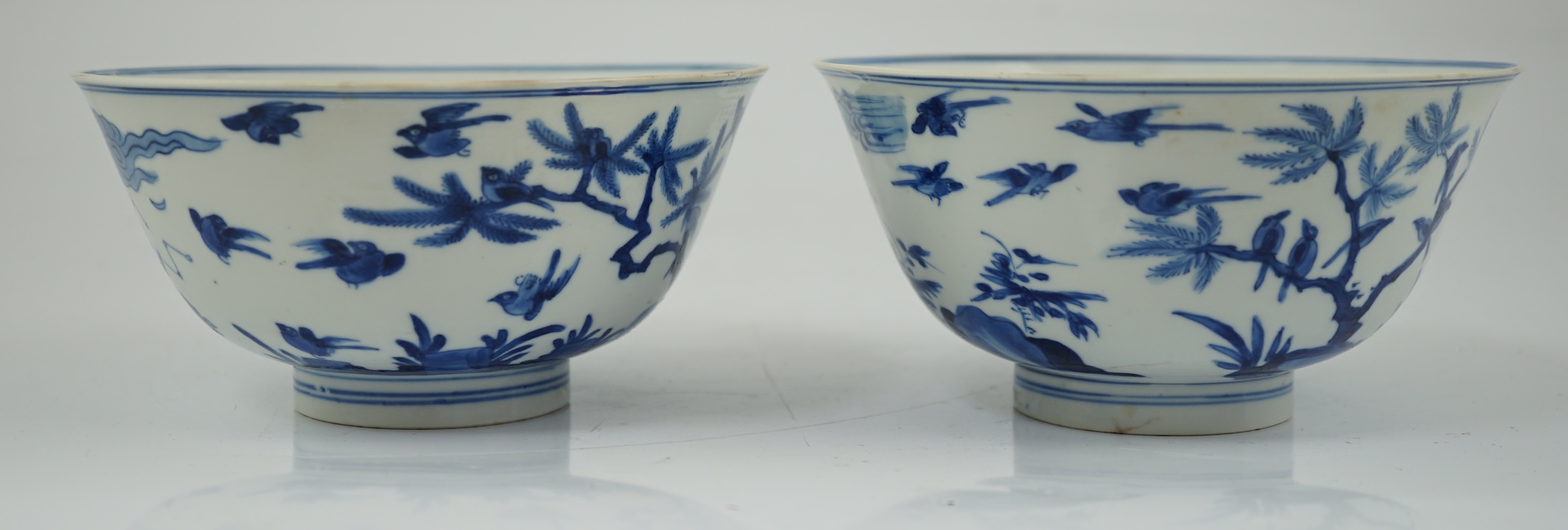 A near pair of Chinese blue and white ‘birds’ bowls, Kangxi period, one bowl restored